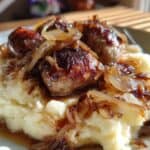 Saftige Bratwürste auf cremigem Püree mit karamellisierten Zwiebeln